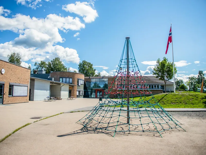 Et klatrestativ og en flaggstang med flagg i toppen, utenfor et bygg.