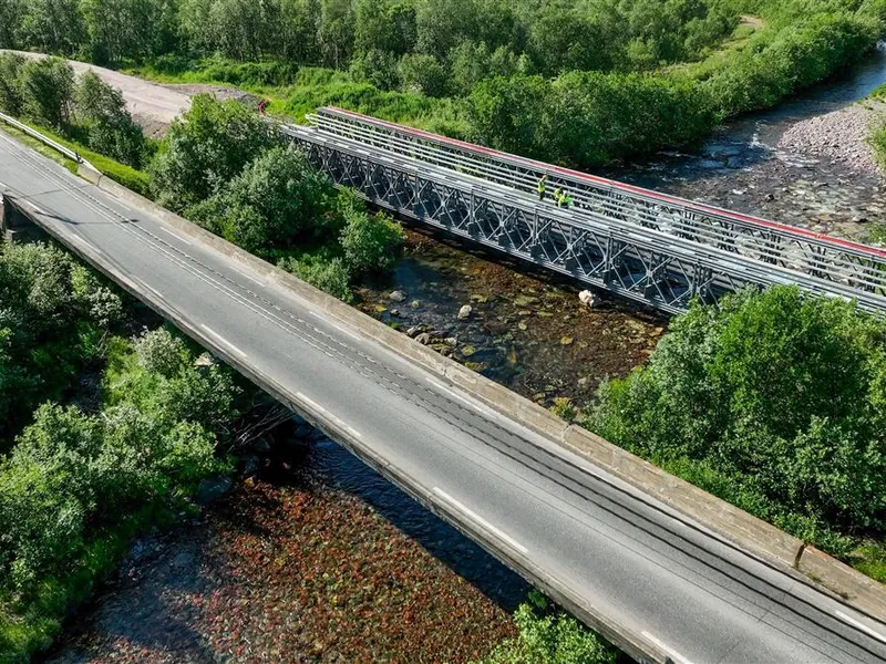 En gammel bru, samt en midlertidig bru, fotografert fra lufta med drone. Fotografert på sommerhalvåret, sola skinner. - Klikk for stort bilde