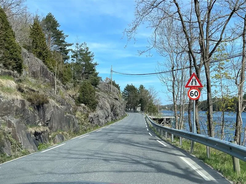 Foto av parti av fylkesveg 411 ved Ulevågkilen, tett på vann og uten grøft mot fjell - Klikk for stort bilde