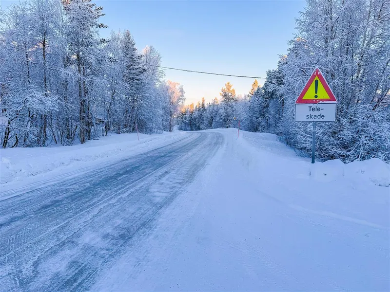 En fylkesveg fotografert på vinteren. Bildet er tatt på dagtid. Man kan se et varslingsskilt hvor det står "Teleskade". - Klikk for stort bilde